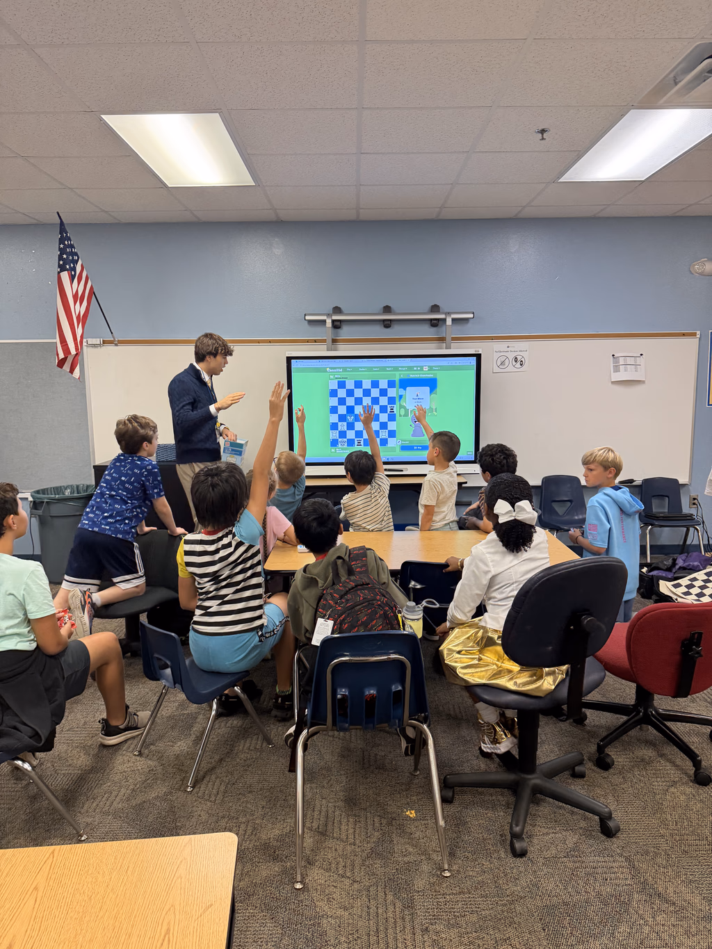 Students raising their hands during an interactive chess lesson